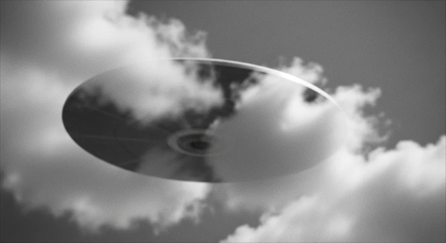 A historical black and white photo of a blurry, disc-shaped object in the sky, with some indistinct 